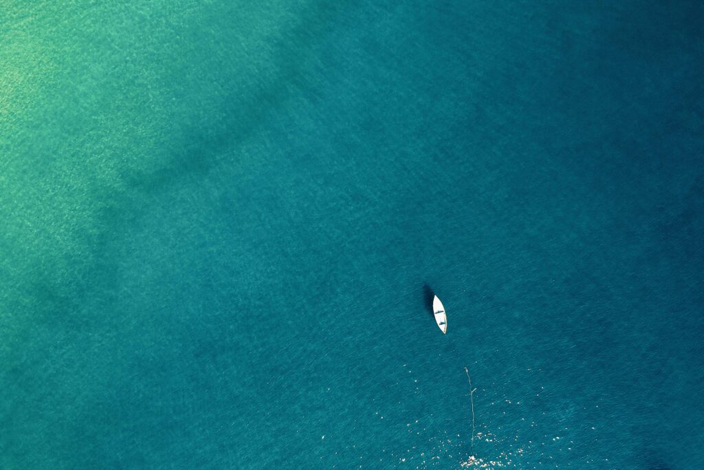 Aerial view of a lone boat on calm turquoise waters, showcasing tranquility.